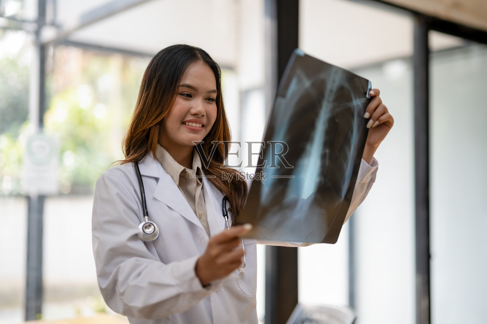 现代诊所里,一位女医生正在仔细检查胸部x光片。照片摄影图片