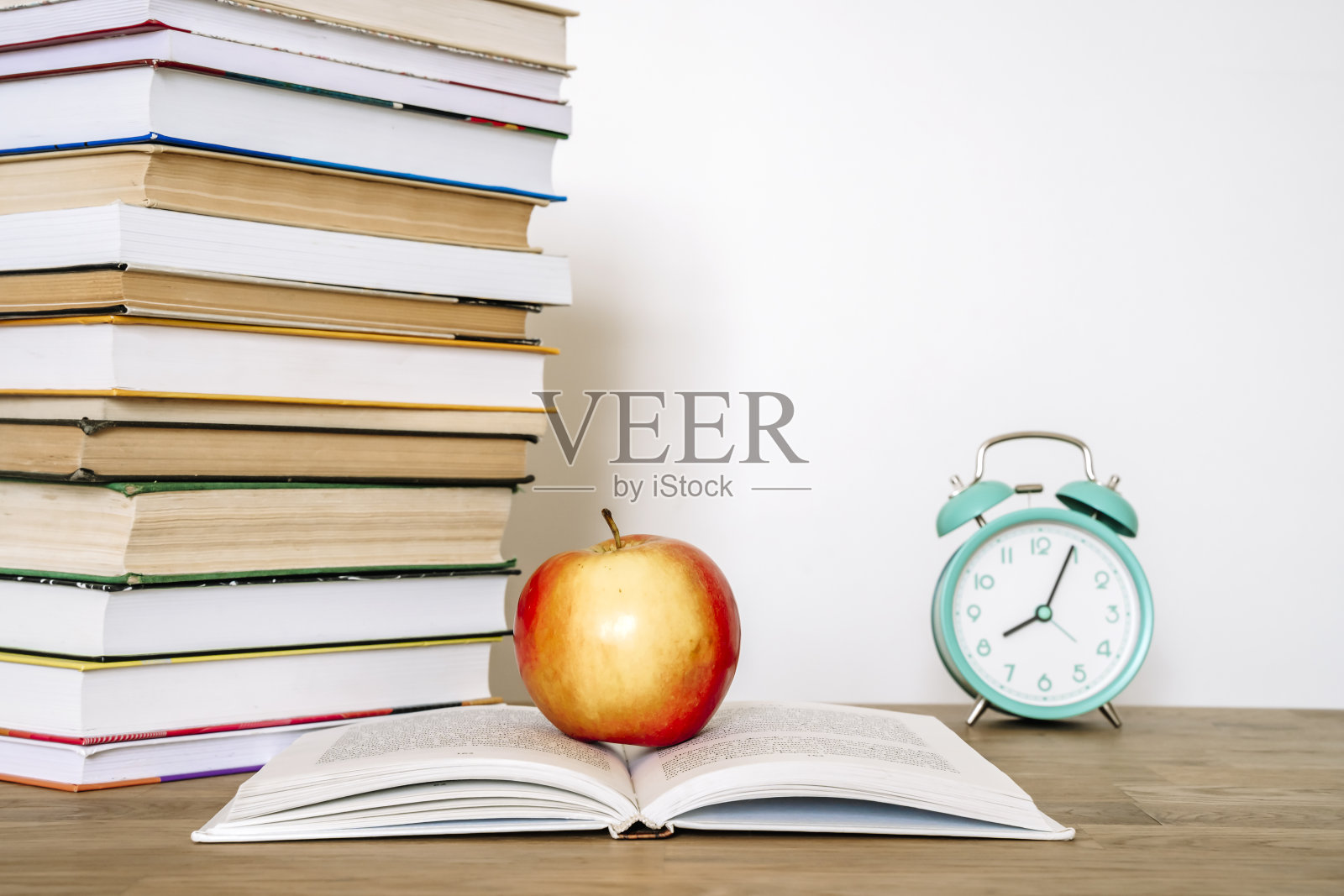 在学校或大学教室的桌子上放着书和一个苹果。学历、学习理念背景照片摄影图片