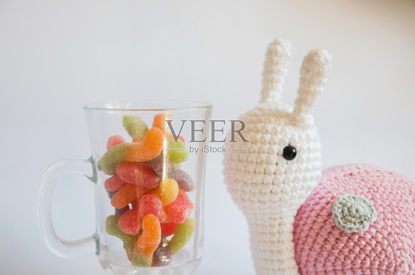 杯子里的彩色糖果和可爱的蜗牛娃娃照片摄影图片