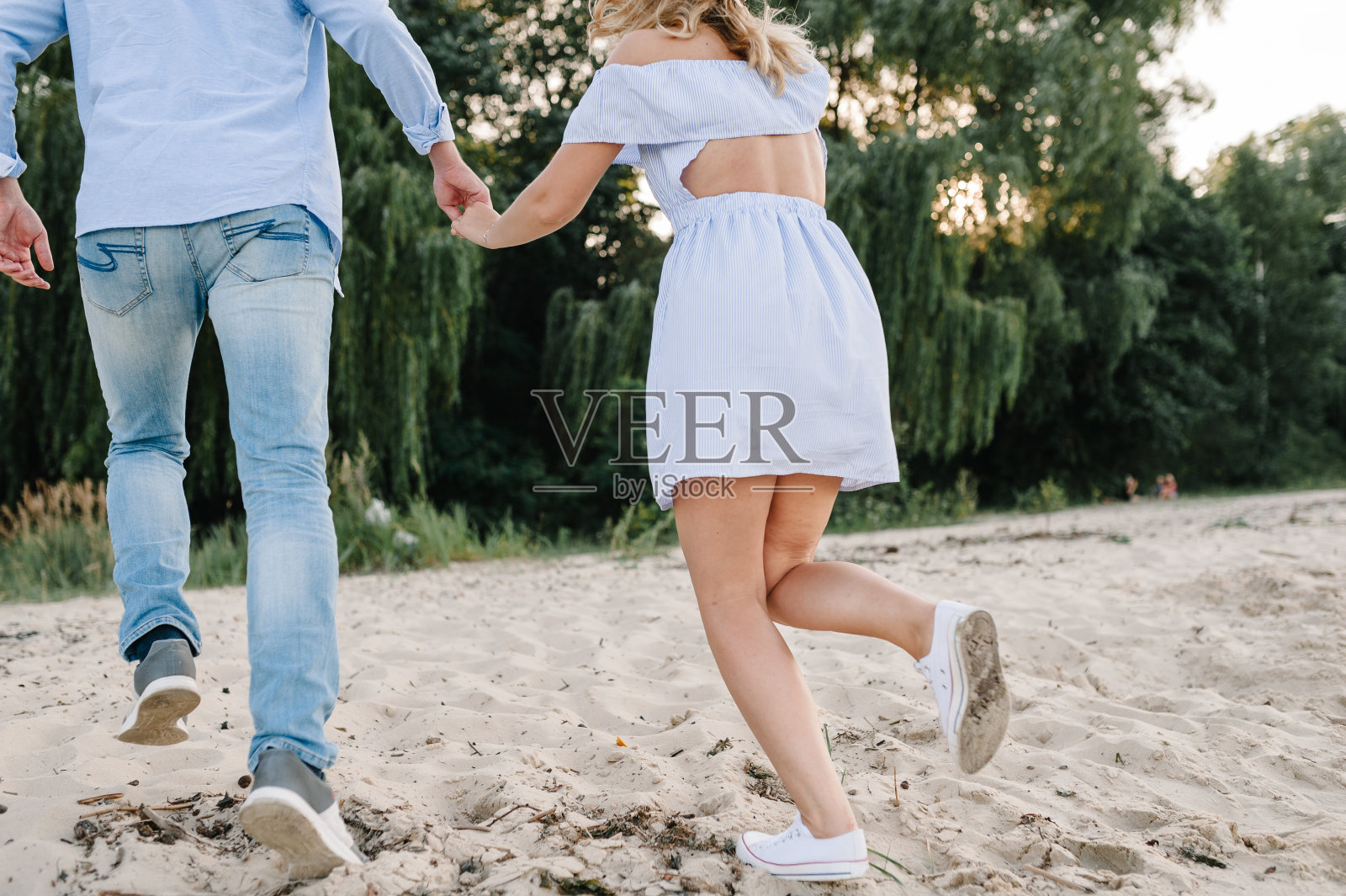 向下看腿。脚的底部视图。男人和女人走在沙滩上。后视图。一对相爱的情侣在海边手牵着手。男女在沙滩上奔跑,享受夏日。共度时光照片摄影图片