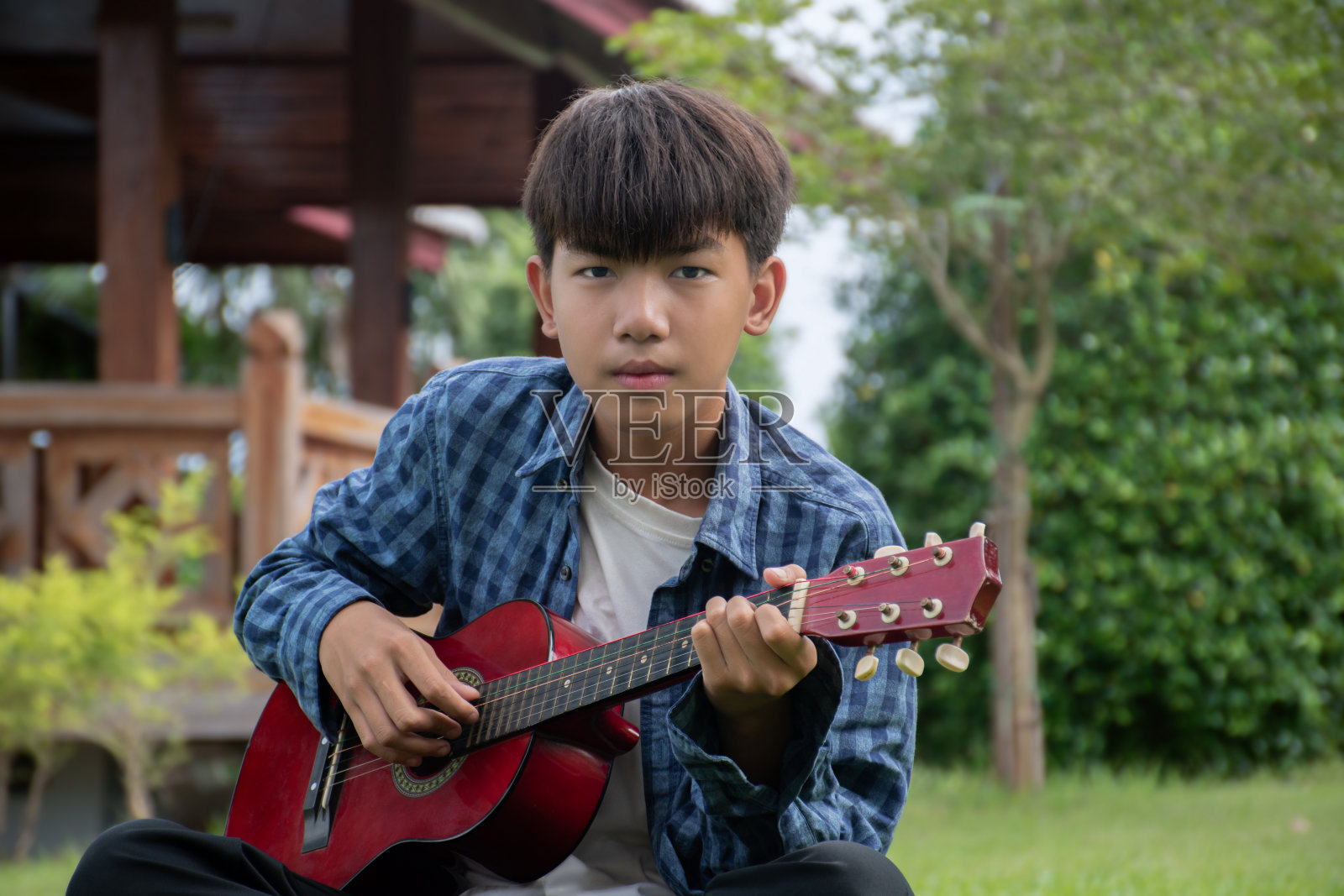 男孩弹原声吉他或四弦琴照片摄影图片