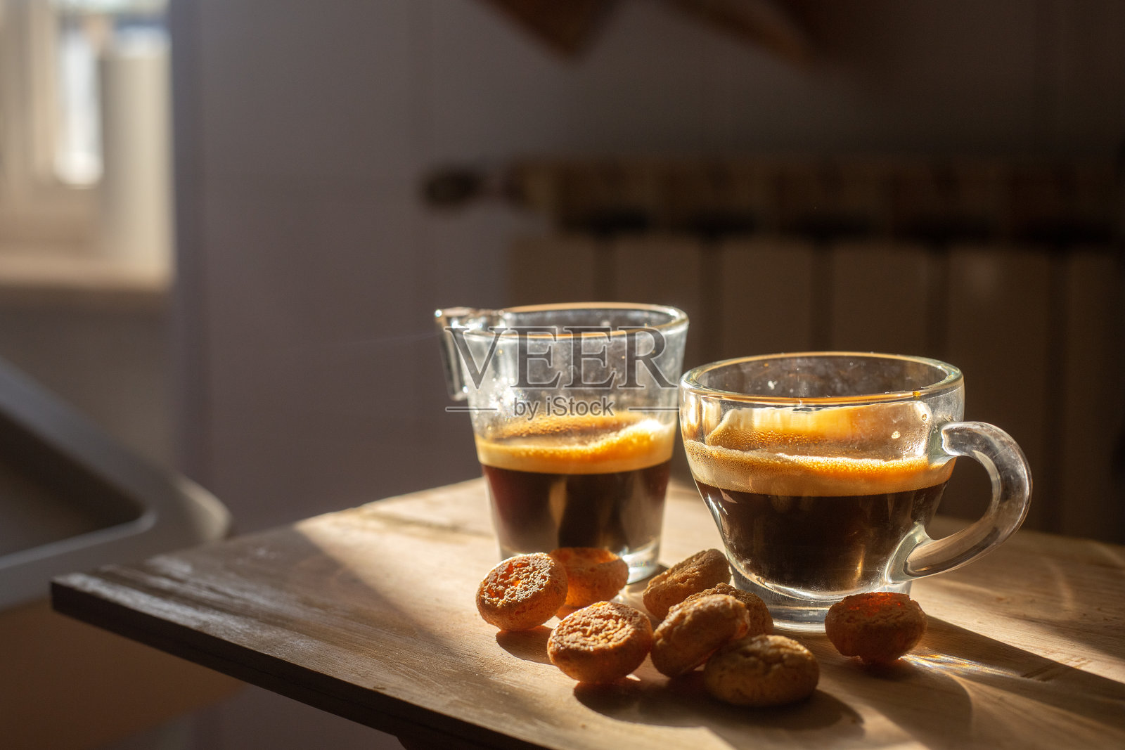 两杯透明的意大利浓缩咖啡,木质表面上有小饼干。高对比度的早晨厨房照片。背景模糊。夫妻自制早餐。壁纸图片照片摄影图片