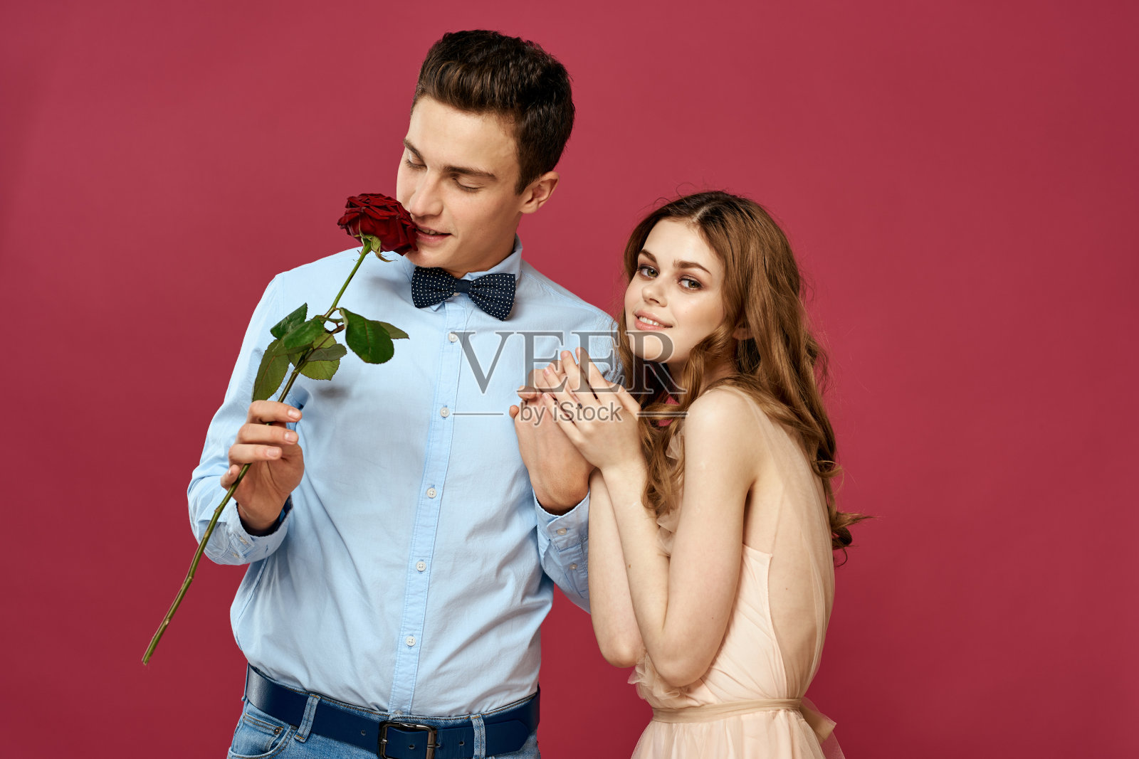 迷恋的男人和女人用一朵红色的花在粉红色的背景拥抱对方复制空间照片摄影图片