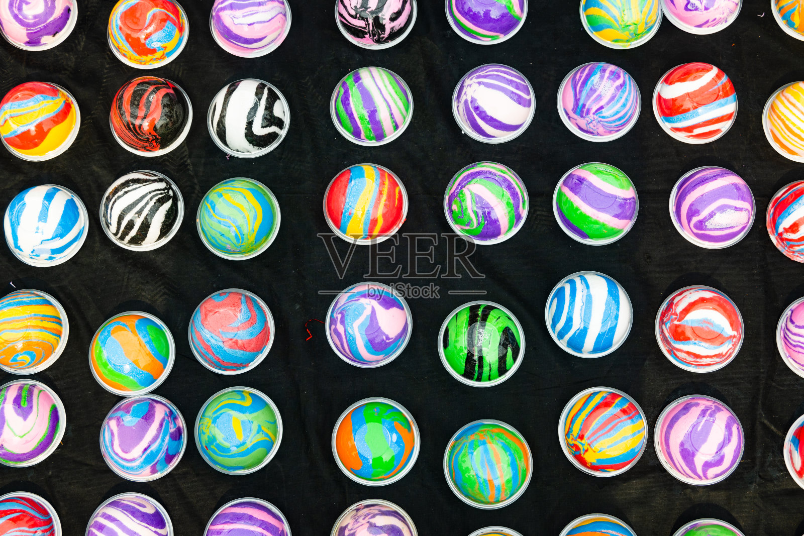 黑色的表面上放着一堆五颜六色的弹珠照片摄影图片