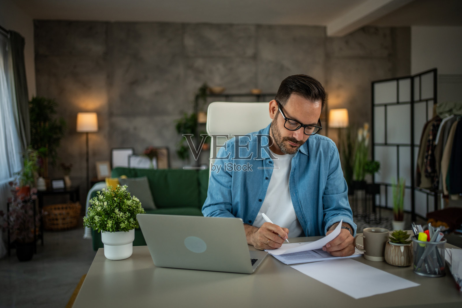 一个全神贯注于工作的成年商人正坐在家庭办公室的办公桌前照片摄影图片