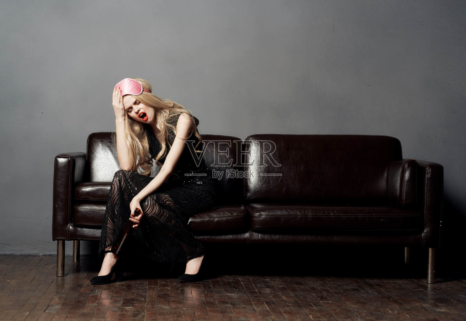 女人在皮沙发上瓶啤酒酒房间灰墙照片摄影图片