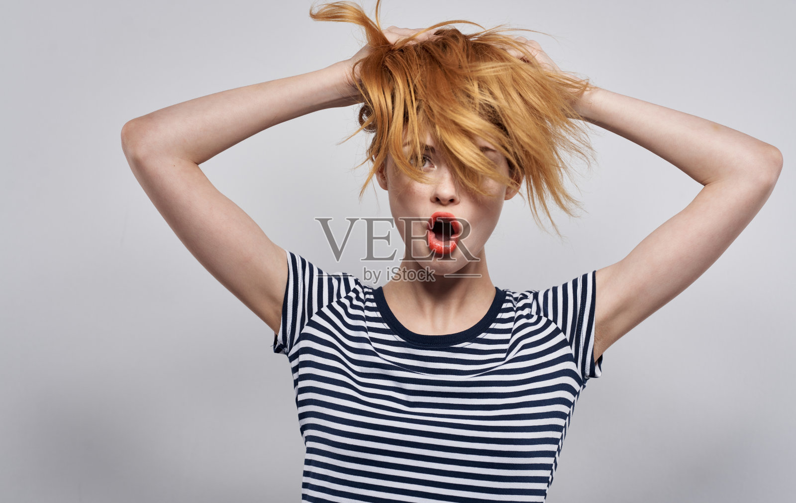 时尚的女人在条纹t恤拿着头发发型微笑照片摄影图片