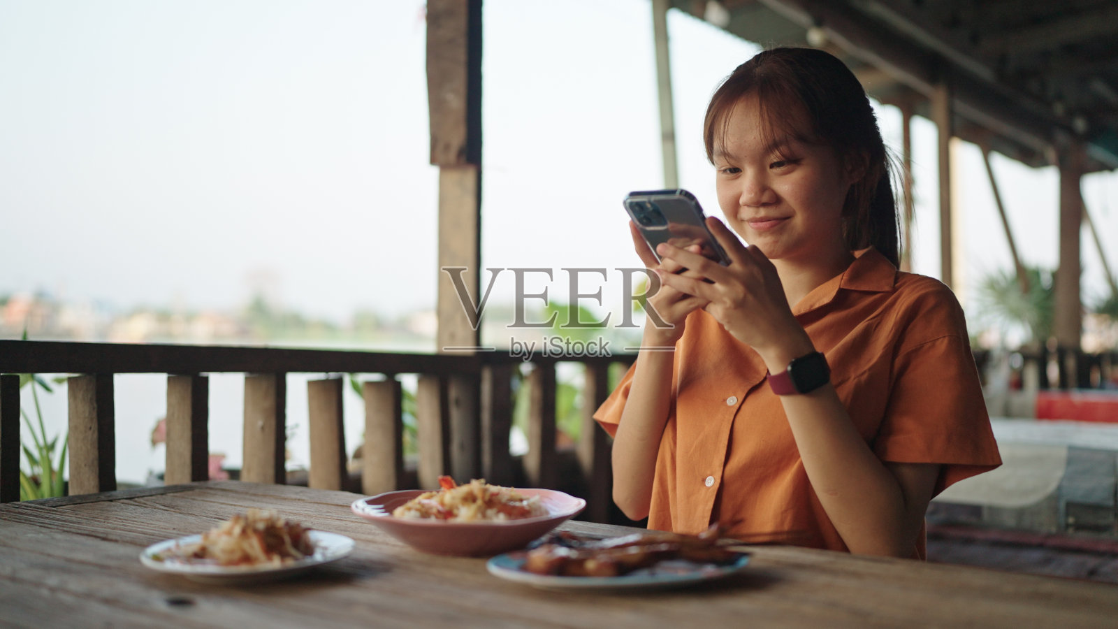 一个十几岁的女孩在当地餐馆给食物拍照。照片摄影图片