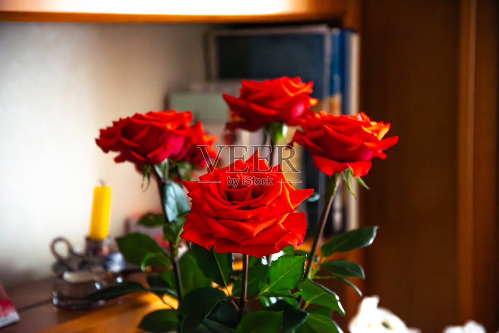房子内部的红玫瑰,后面的部分展示了熄灭的蜡烛照片摄影图片