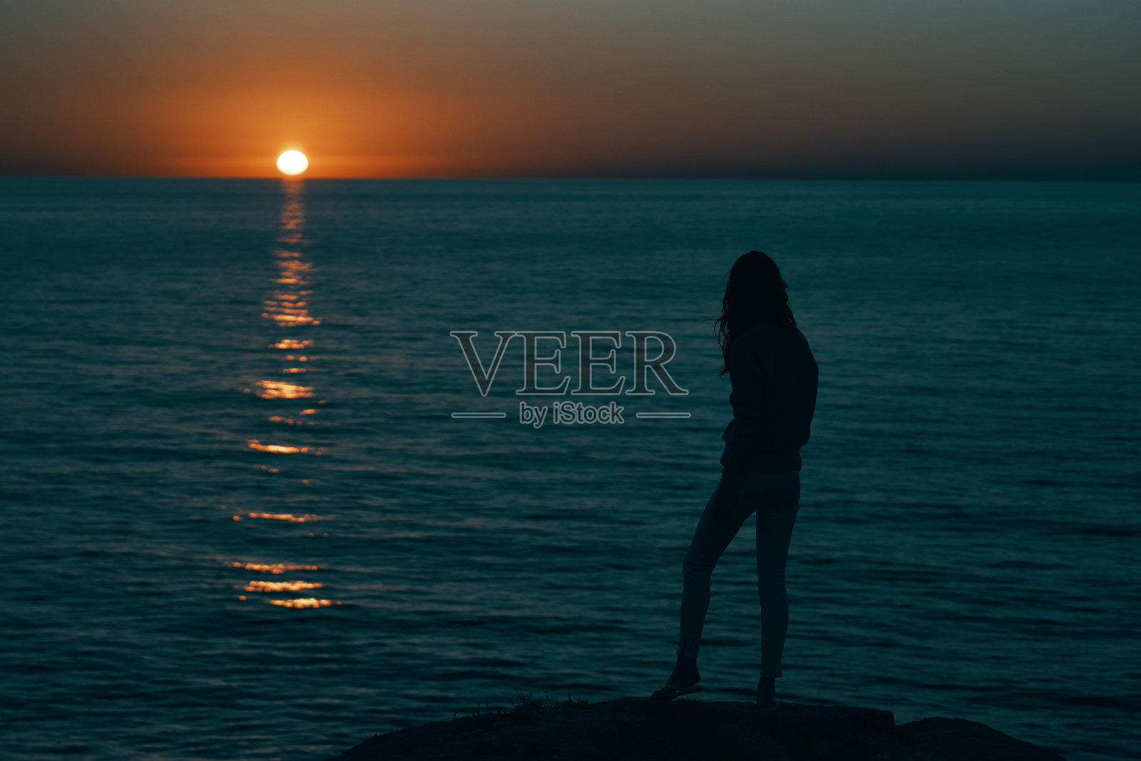 日落时分,海边山上的女人举起了手照片摄影图片