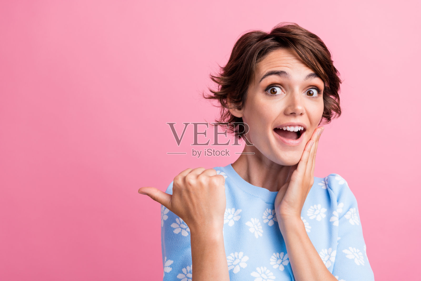 惊讶的积极的人的肖像,手触摸脸颊,指示手指空白的空间孤立在粉红色的背景照片摄影图片