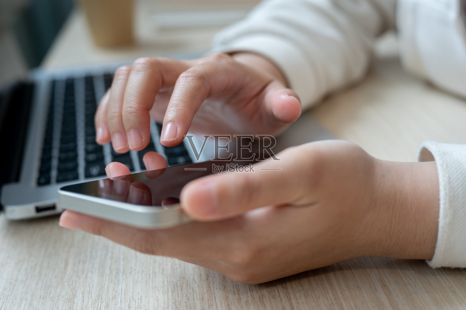 一个女人在工作时触摸她的智能手机屏幕,查看信息的特写照片。照片摄影图片