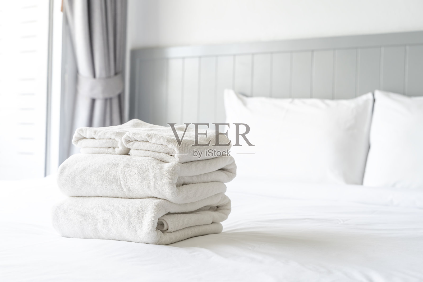 床上有一叠白毛巾。毛巾叠得整整齐齐,叠在一起。照片摄影图片