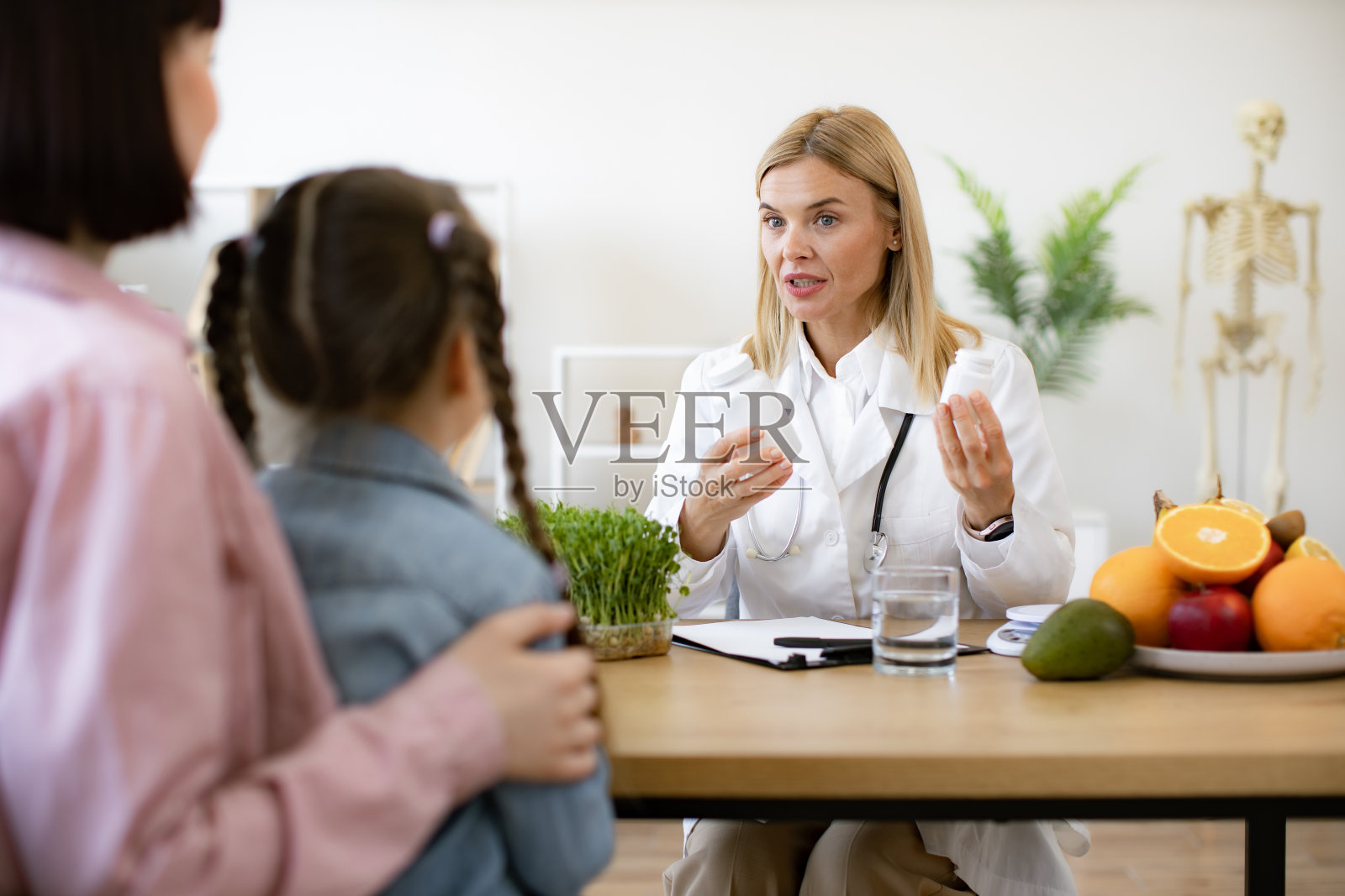 成熟的儿科医生在现代诊所接待女病人。照片摄影图片