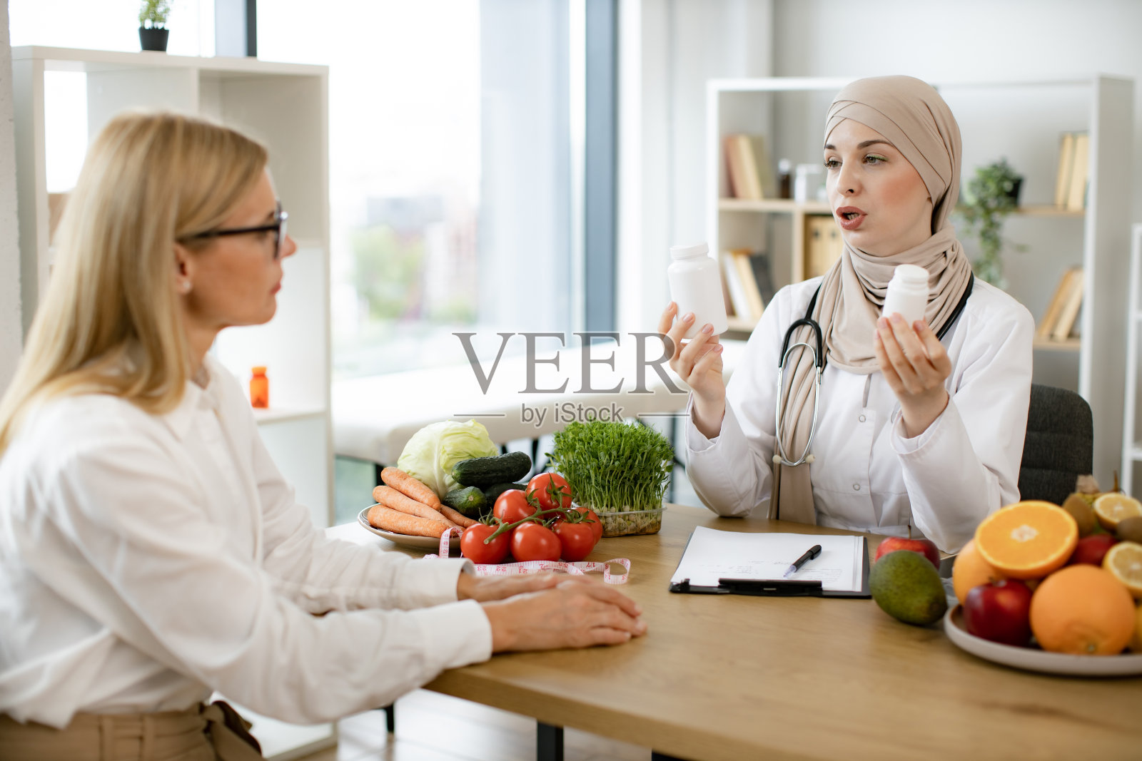 戴头巾的穆斯林医生在现代诊所接待女病人。照片摄影图片