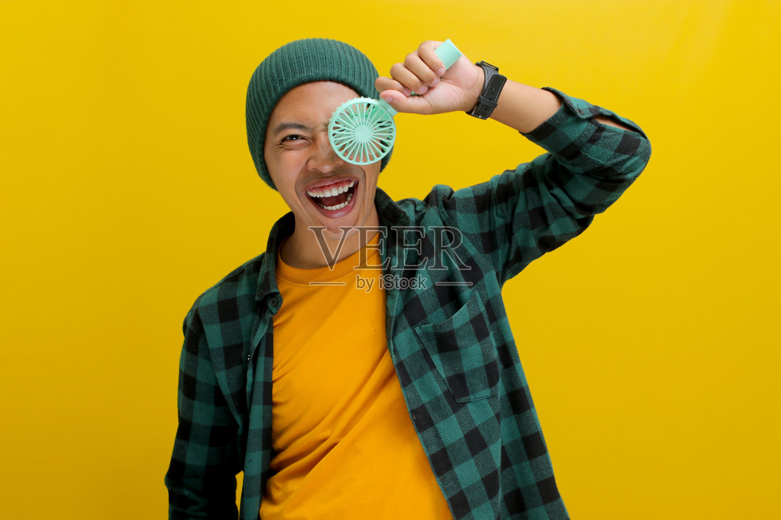 年轻的亚洲男子拿着一个手持便携式迷你电风扇照片摄影图片