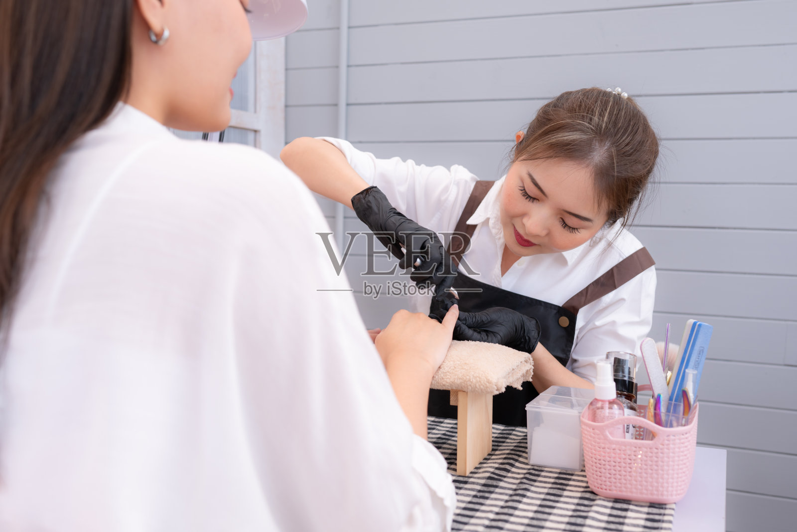 美甲师正在使用工具为客户剪指甲和打磨指甲。照片摄影图片