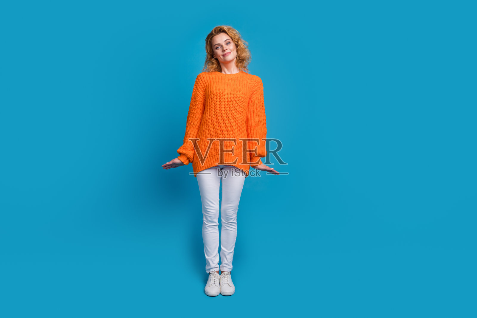 漂亮可爱的女人穿着时髦的橙色衣服,在蓝色的背景上孤立的全身照片照片摄影图片