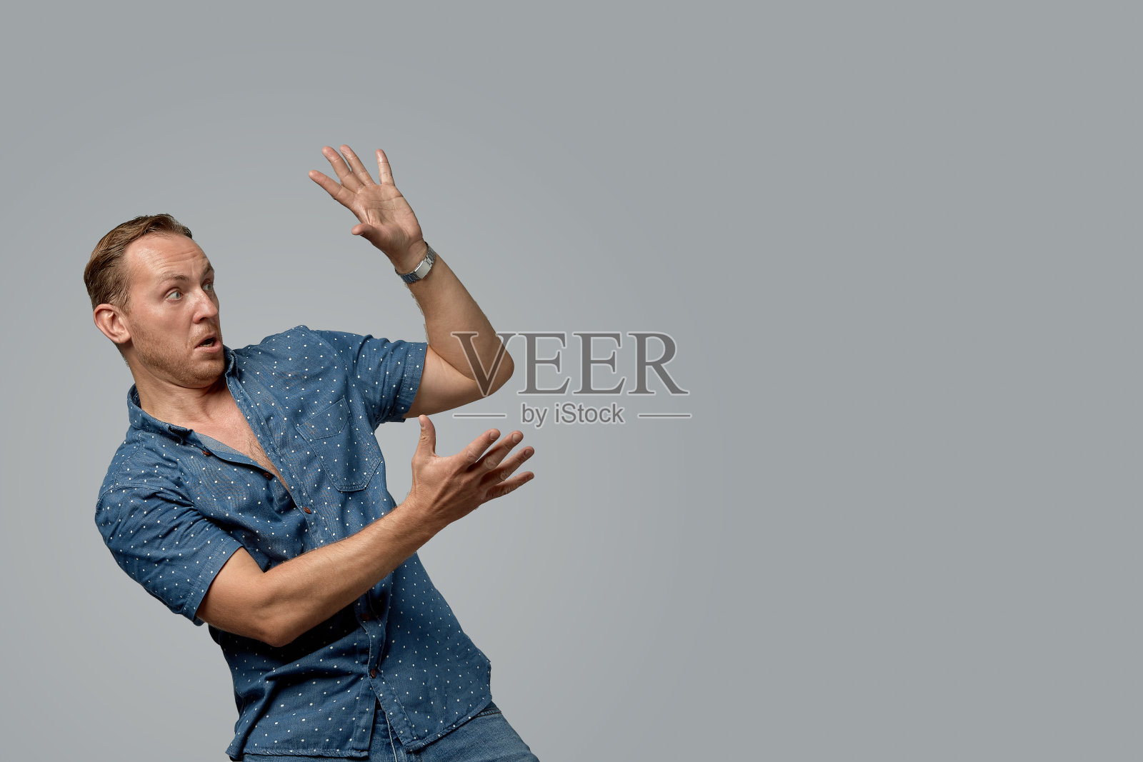 一个穿衬衫的男人把手放在你的文字或灰色背景的广告上。概念横幅广告,文案空间,灰色背景,商业设计照片摄影图片