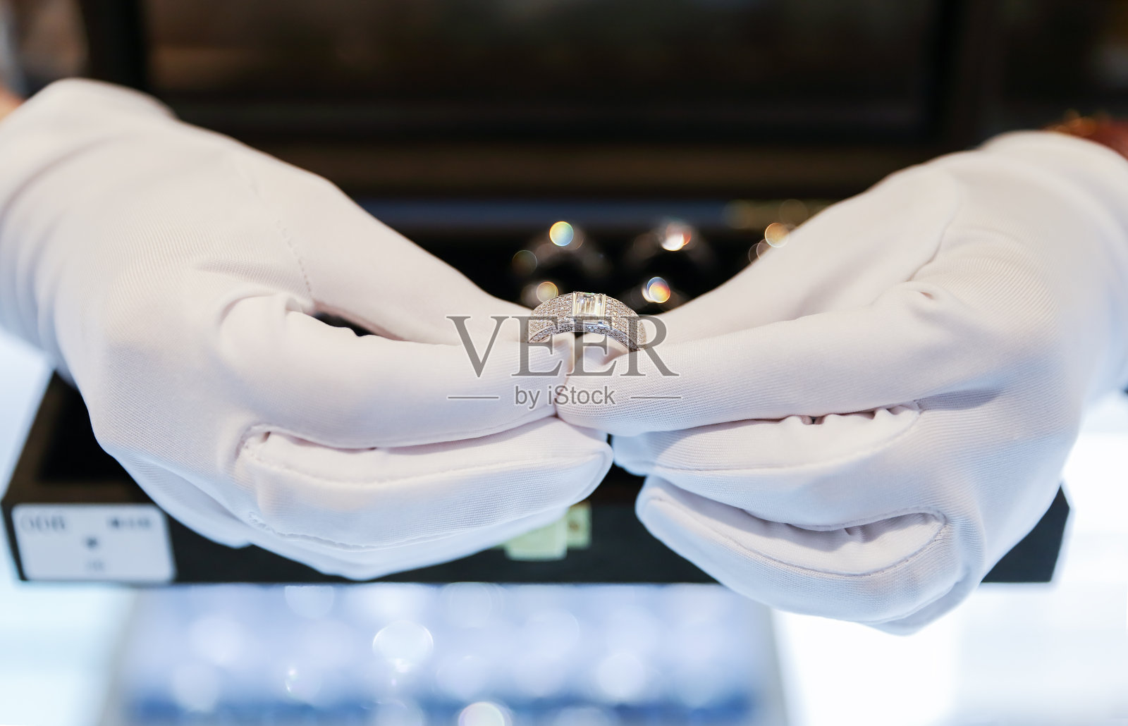 高级珠宝店的女职员戴着白手套向顾客介绍钻戒照片摄影图片