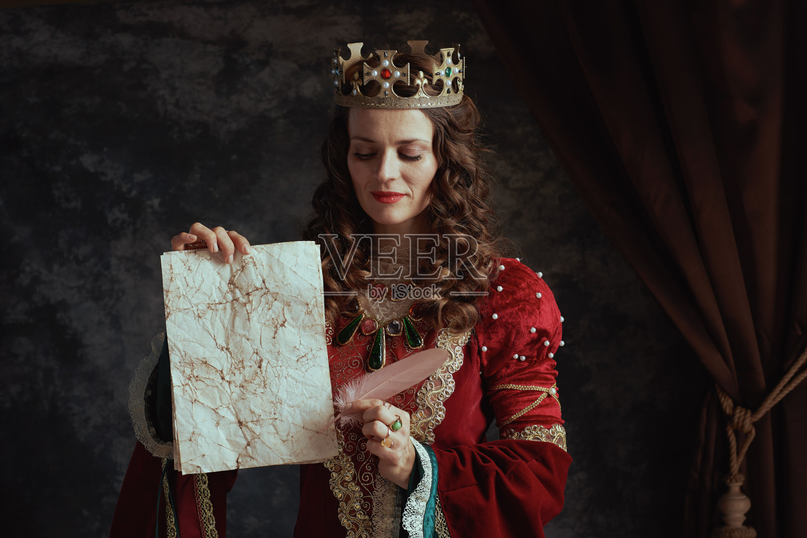 中世纪女王,身穿红色长裙,手拿羊皮纸,头戴王冠照片摄影图片