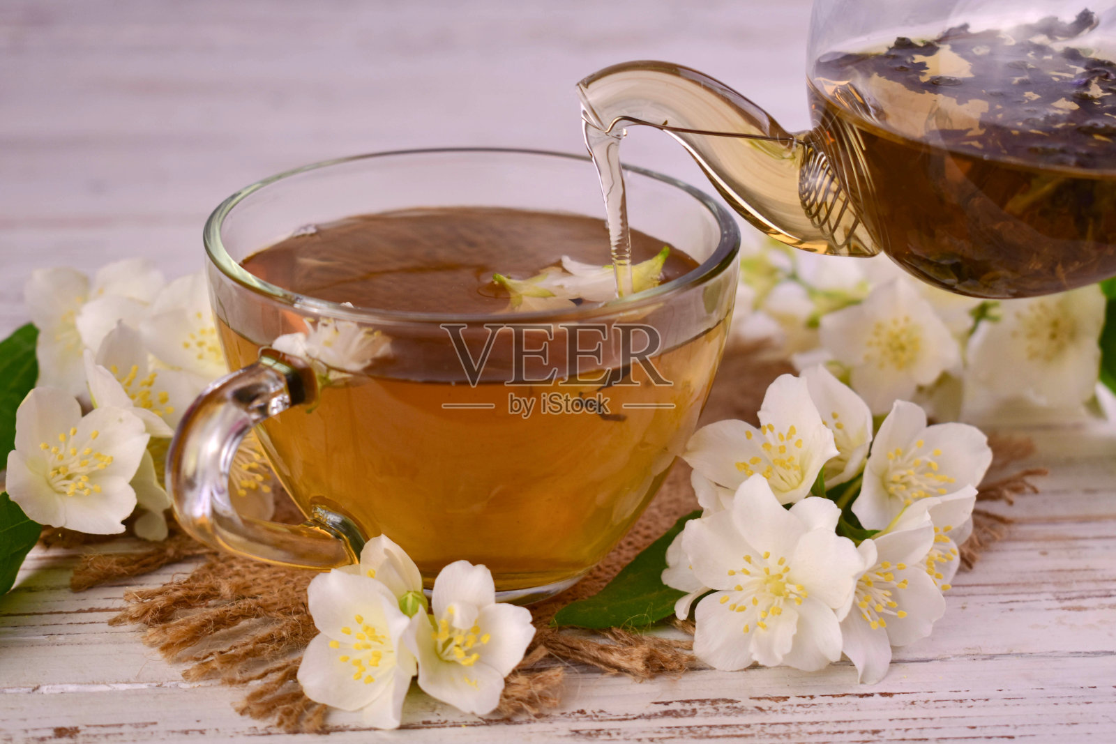 透明杯子里的茉莉花茶,木质背景。照片摄影图片