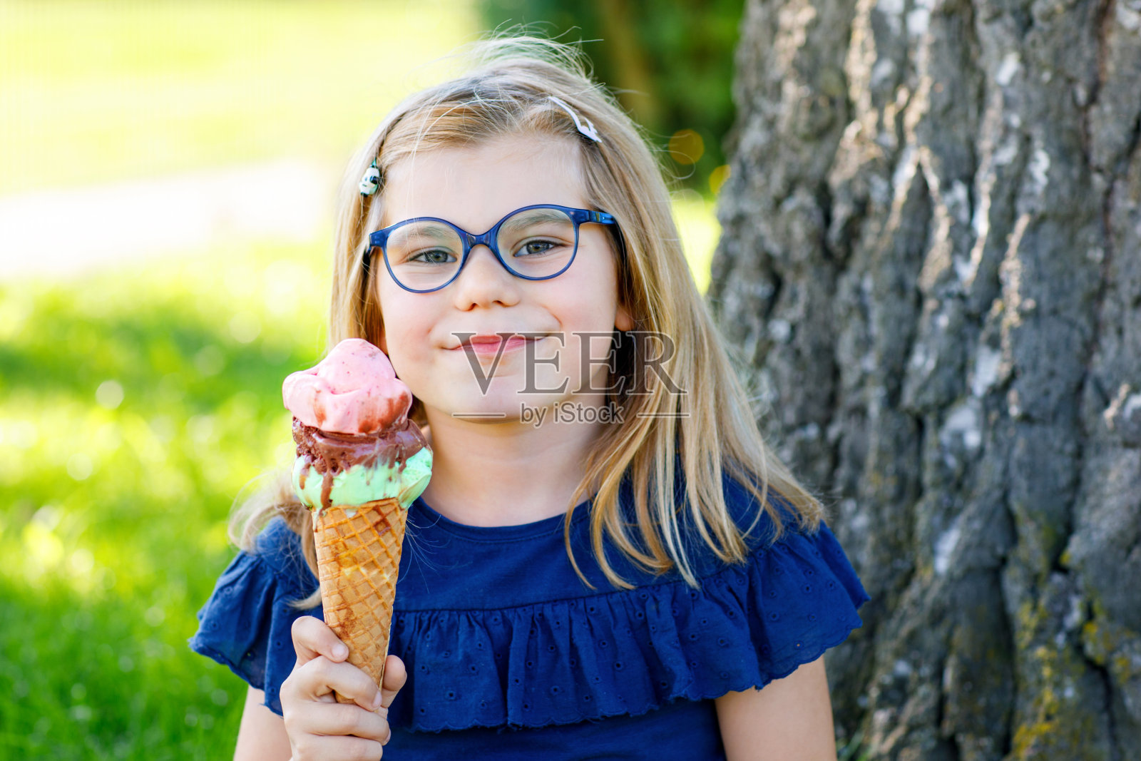 快乐的学龄前女孩在阳光明媚的夏日吃着五颜六色的华夫蛋筒冰淇淋。蹒跚学步的孩子吃冰淇淋甜点。在炎热温暖的夏日里吃甜食。明亮的灯光,五颜六色的冰淇淋。照片摄影图片