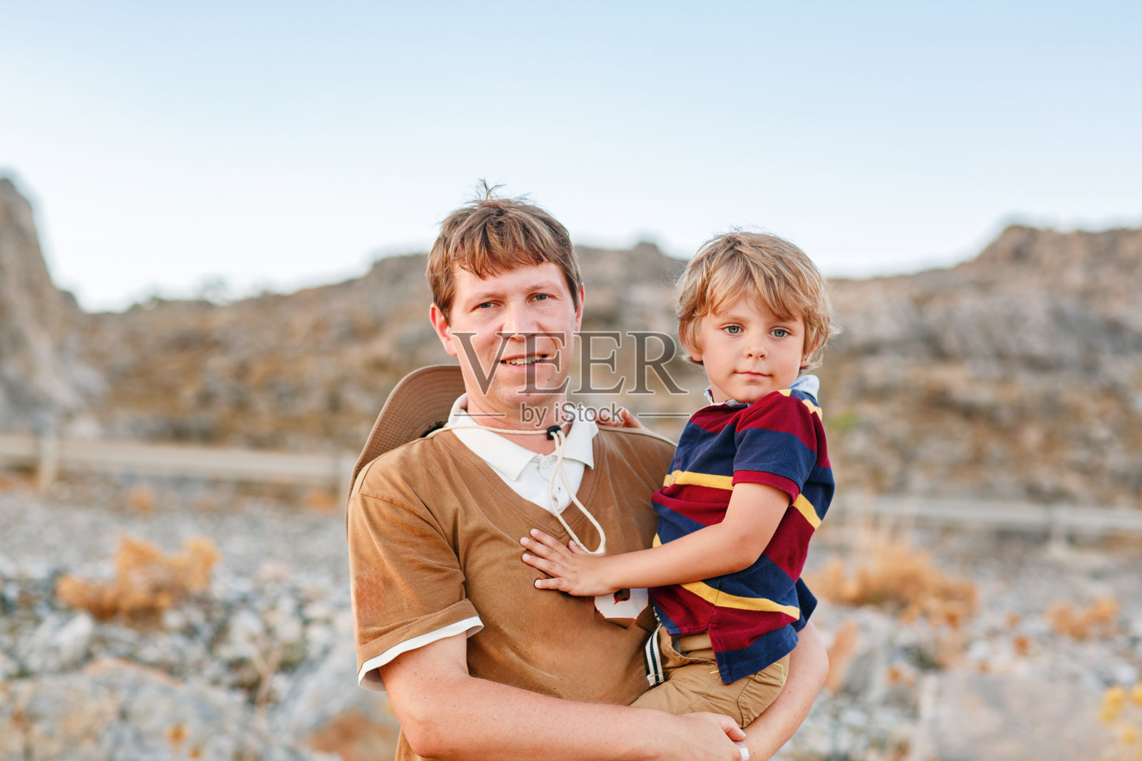 父子俩在大峡谷中穿越美国西部。快乐的小孩和年轻人。爸爸抱着男孩。看山照片摄影图片