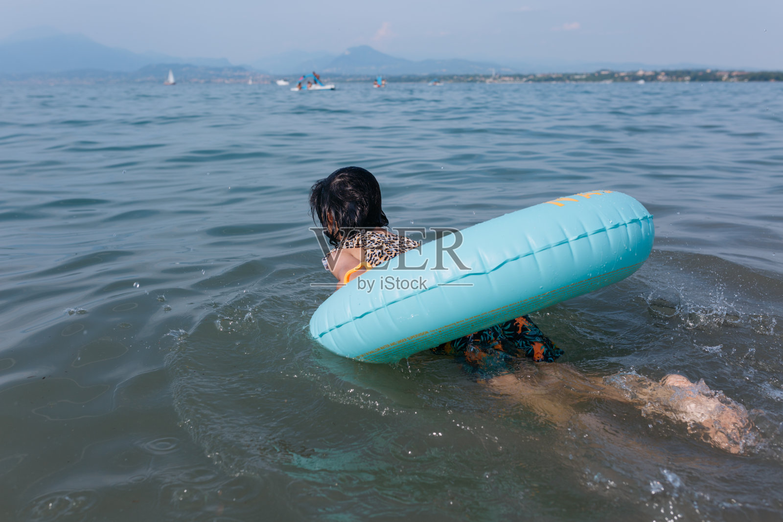 孩子在水里游泳,借助充气环照片摄影图片