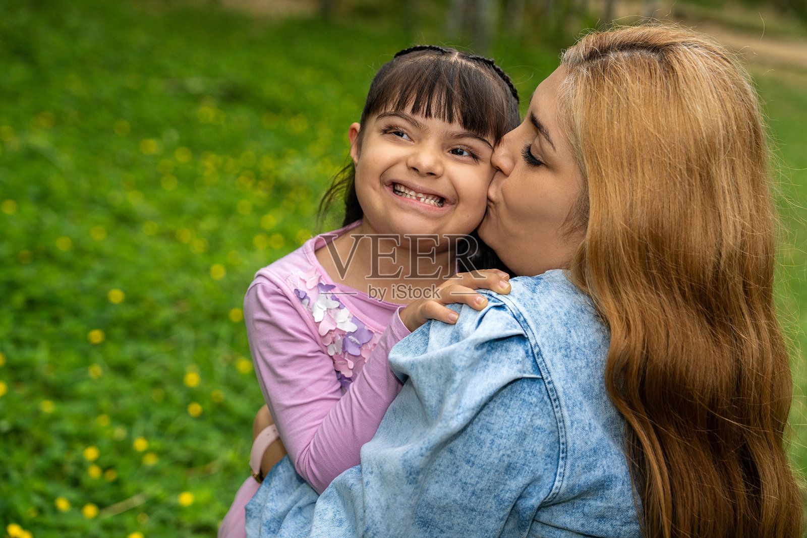 妇女在城市公园里抱着患有唐氏综合征的孩子照片摄影图片