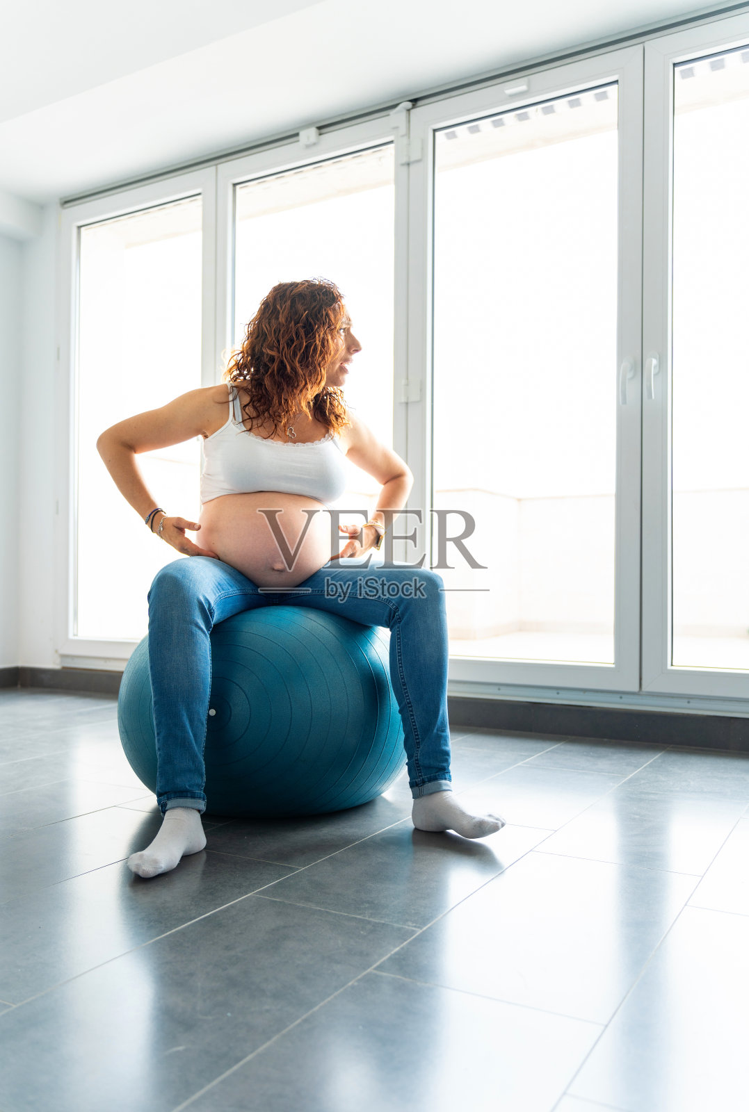 一位红发中年孕妇坐在孕球上照片摄影图片