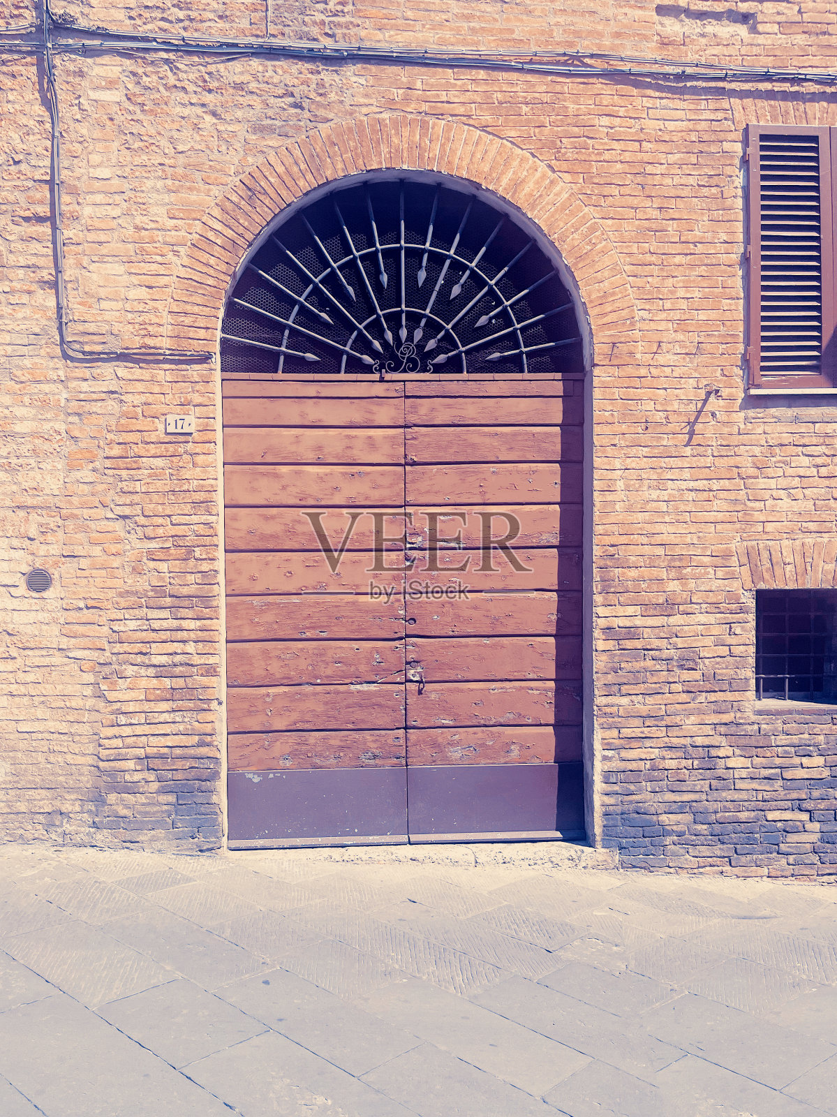 美丽的木门,有一个由砖和金属制成的拱形入口,沿着老城的道路照片摄影图片