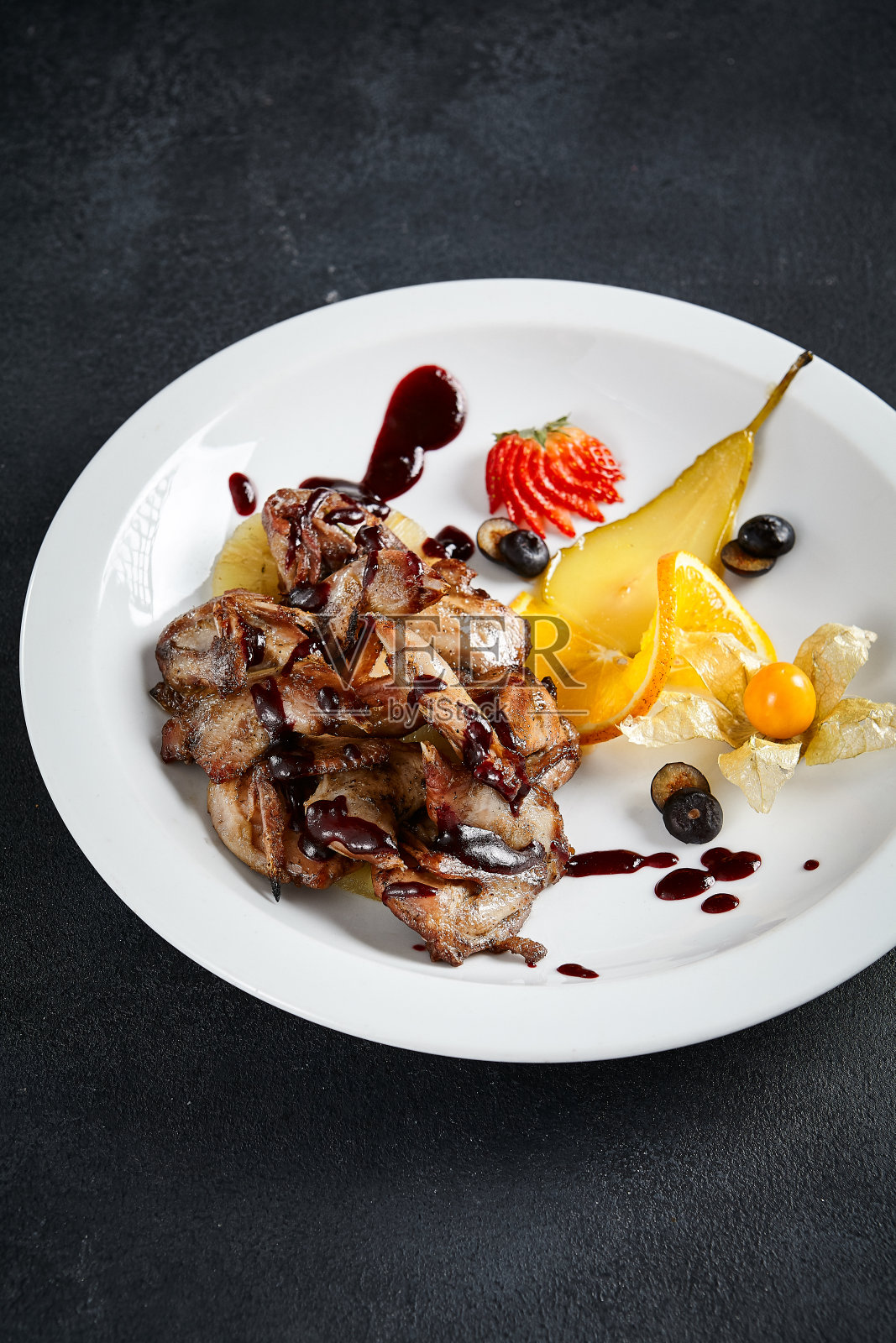 美味的照烧鸡翅与充满活力的水果搭配在有质感的黑色餐桌上。在烹饪呈现中,品味与优雅的交响乐照片摄影图片
