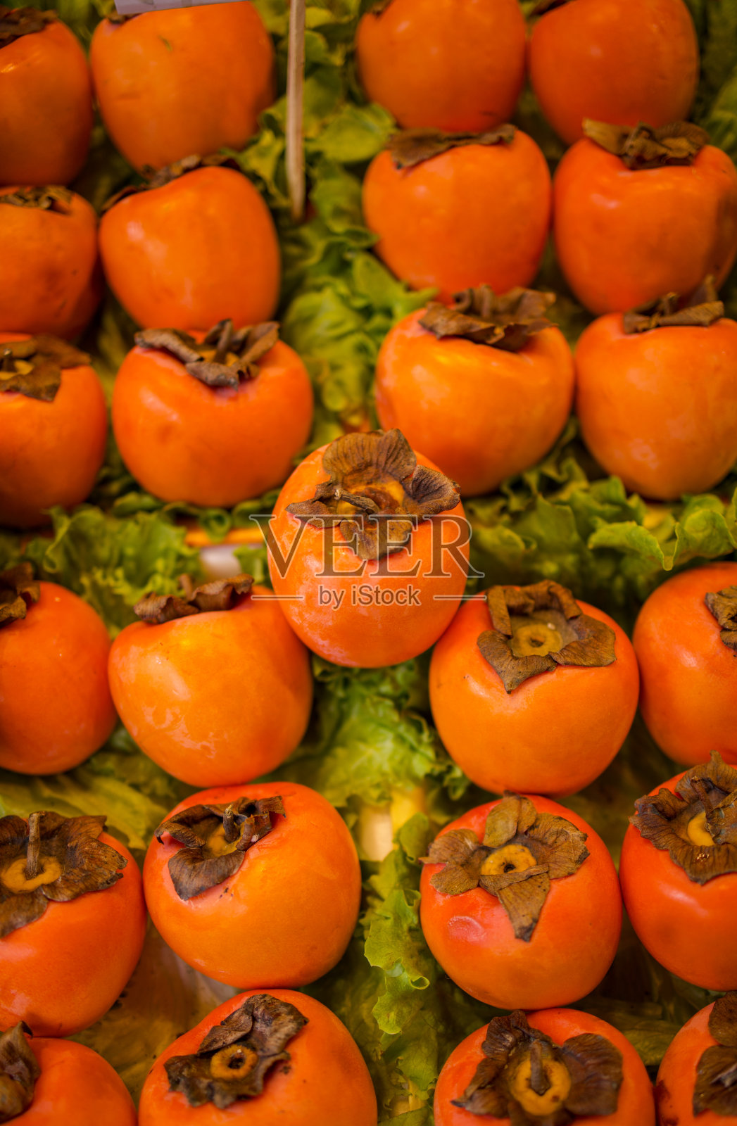 在Kadıköy历史市场,柿子排成一排。照片摄影图片