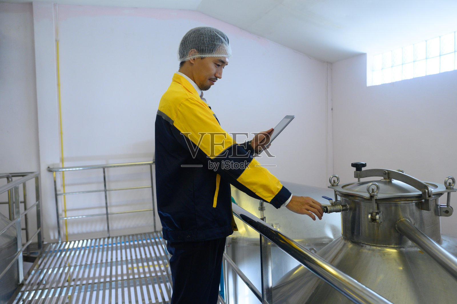 葡萄酒检查员在大型现代酒庄的饮料行业工作,并在酒庄仓库测试葡萄酒。照片摄影图片