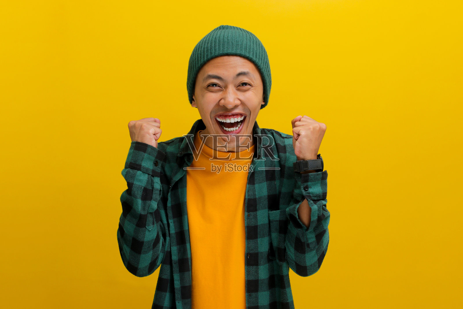 兴奋的年轻亚洲男子正在表达喜悦和庆祝胜利与拳头拳或“是”手势照片摄影图片