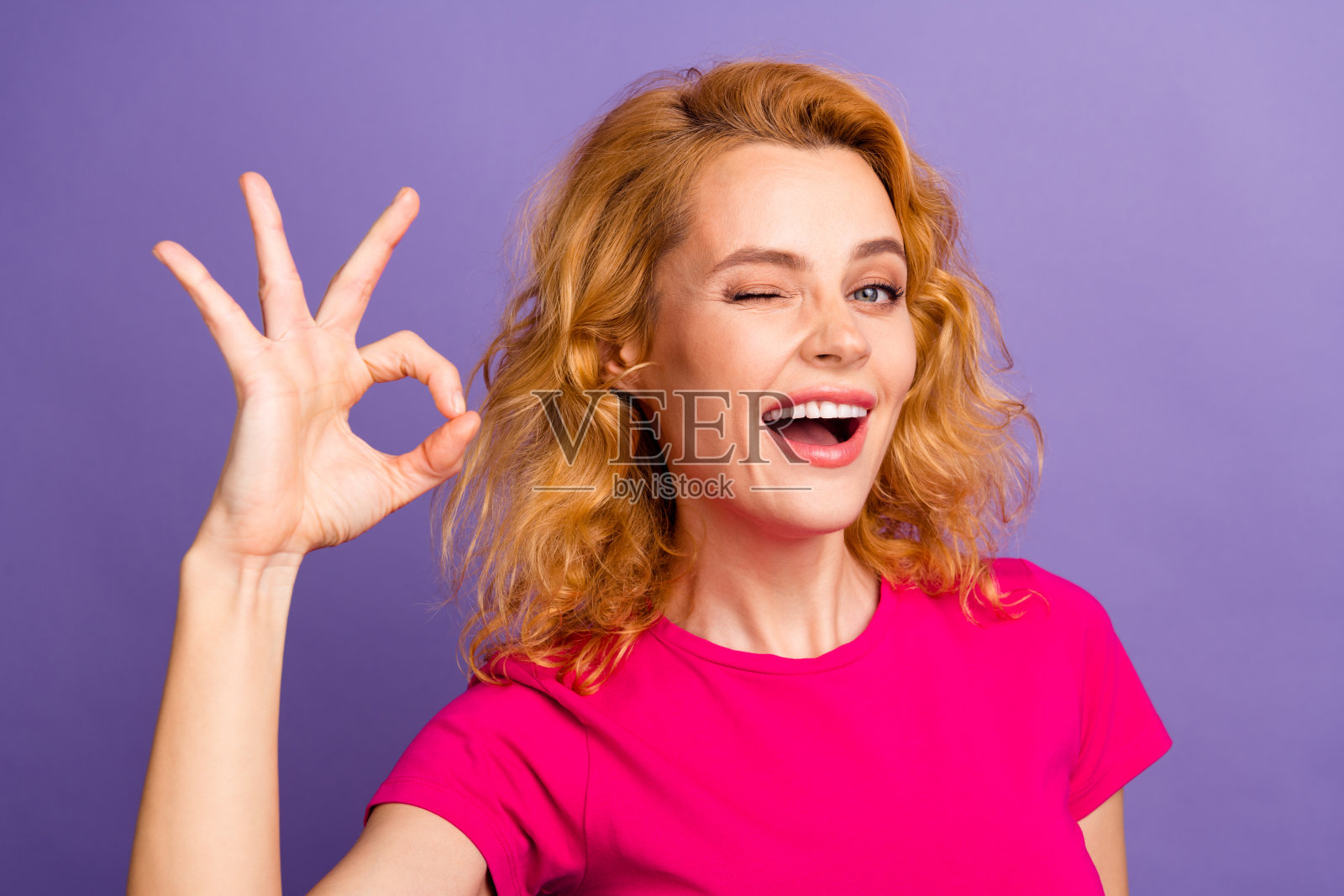 迷人的漂亮的酷女人穿着时尚的粉红色衣服的照片,在紫色的背景上孤立的标志照片摄影图片