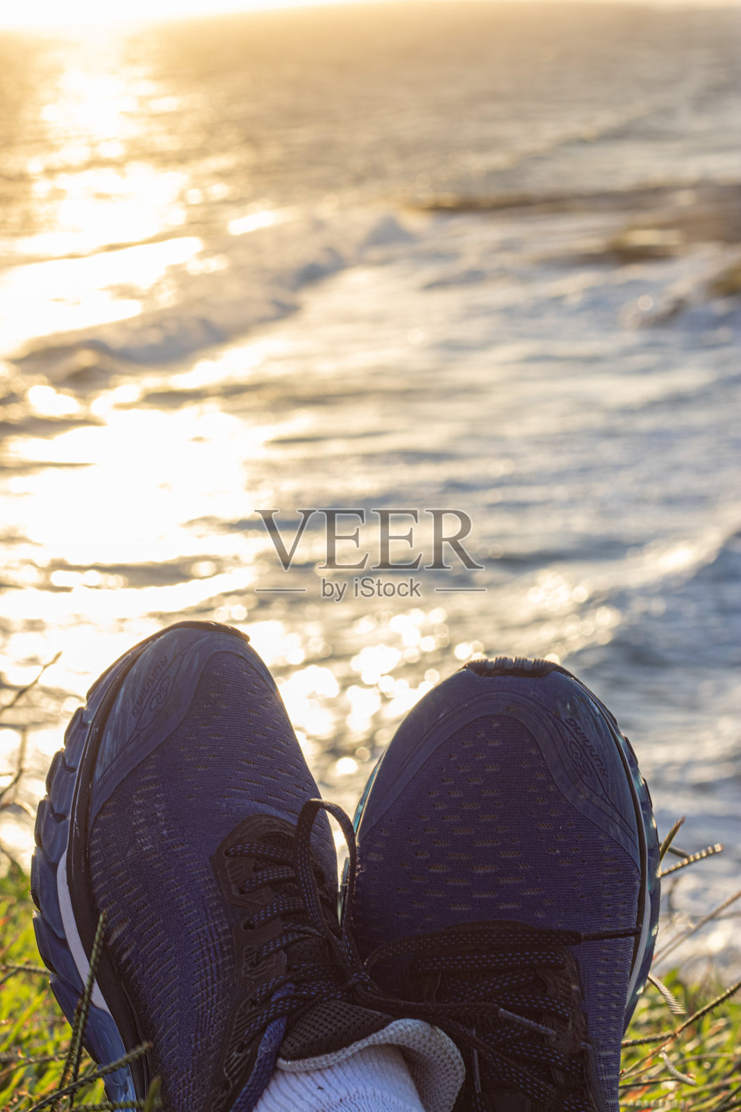 在海边看日落的人的身体的一部分。照片摄影图片