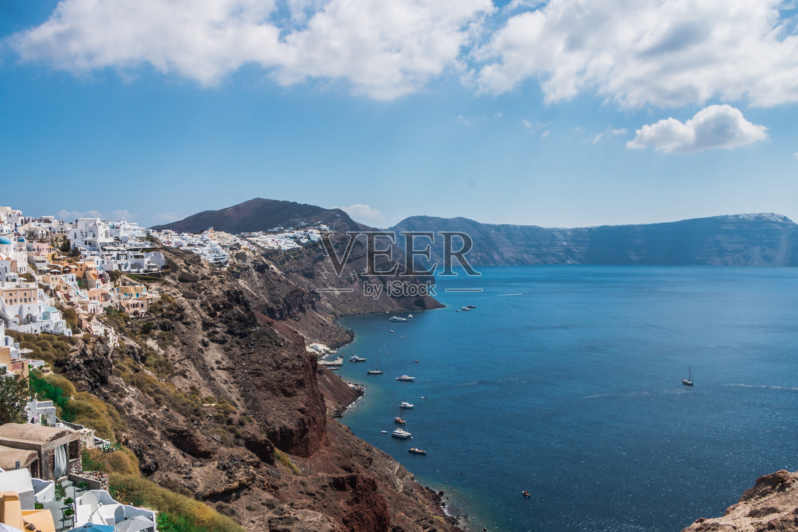希腊圣托里尼岛上的小镇。传统而著名的房子和教堂,蓝色的圆顶俯瞰着爱琴海的火山口照片摄影图片