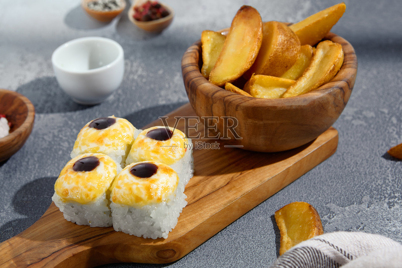 烤寿司卷,配上奶油配料和金色的马铃薯角,在木板上呈现出融合的味道照片摄影图片