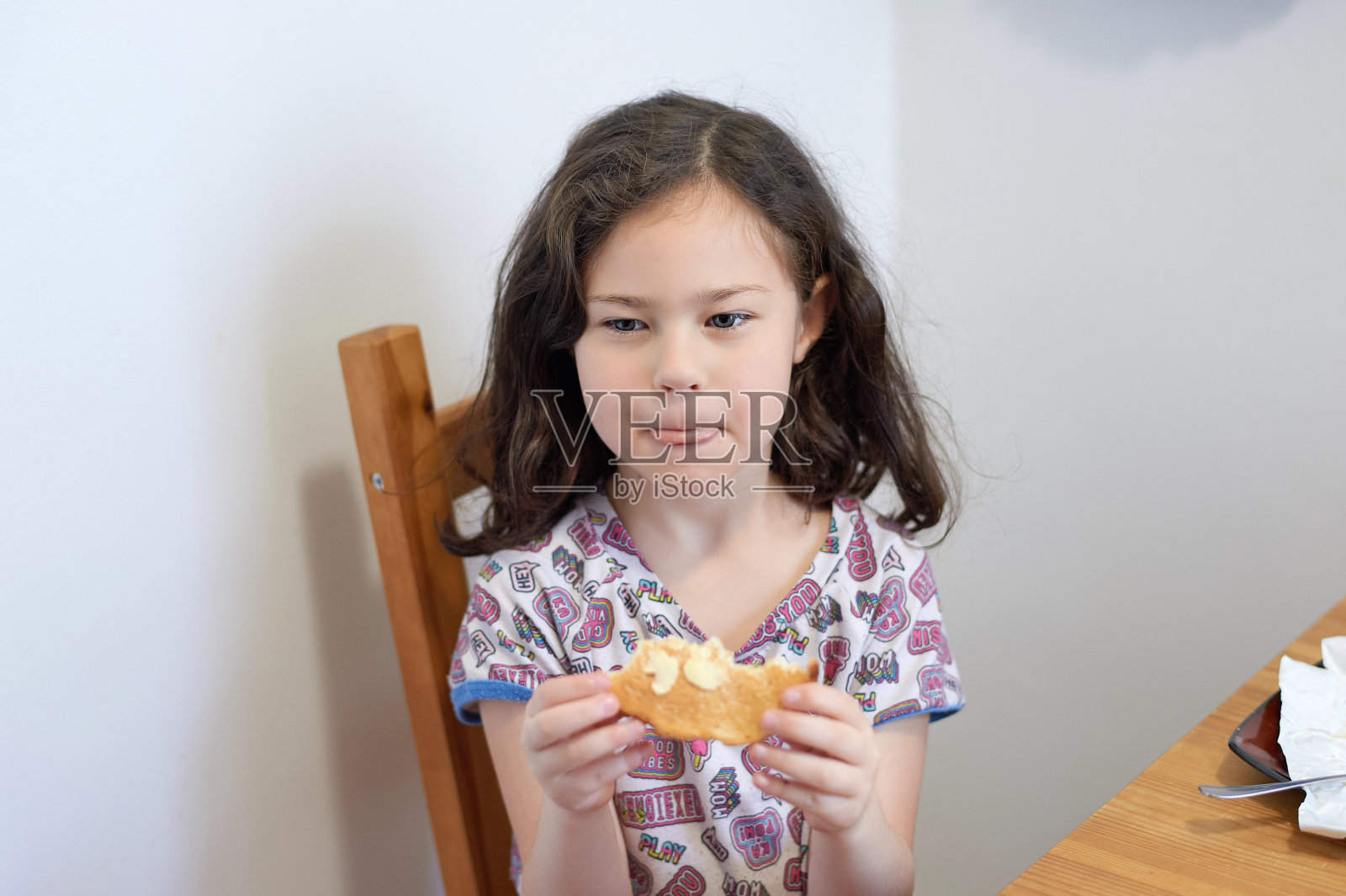 漂亮女孩在厨房餐桌上吃着抹黄油的吐司当早餐照片摄影图片