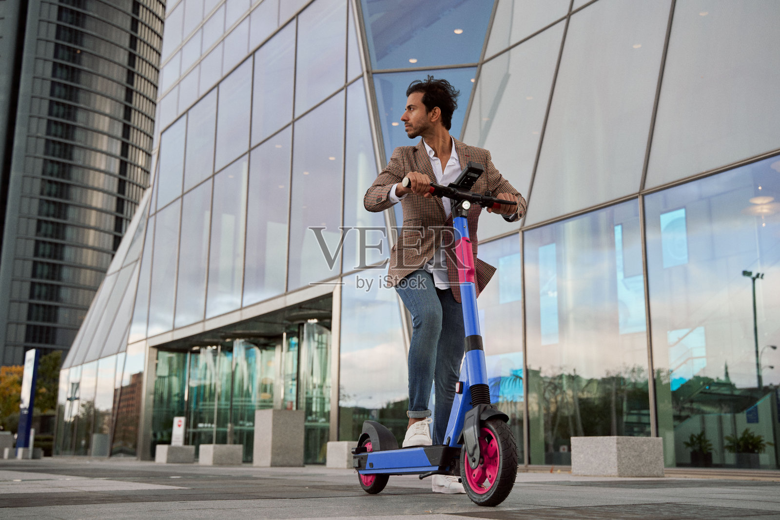 印度商人骑着他的电动滑板车走在商业区。绿色城市交通概念照片摄影图片