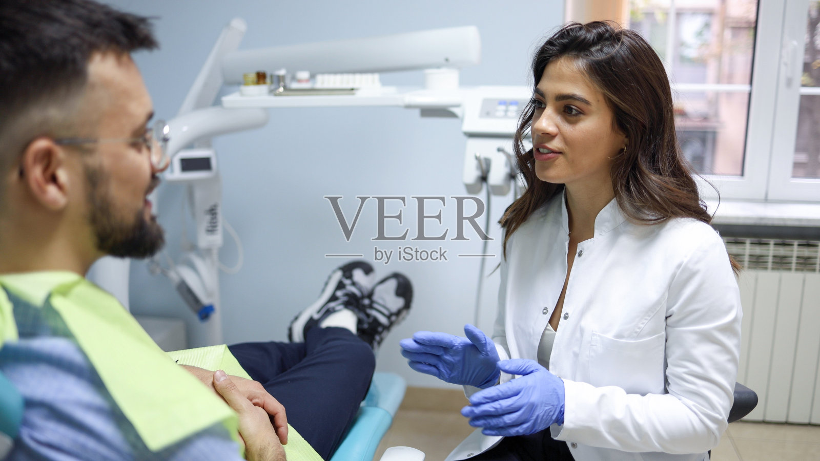 女牙医和她的病人在治疗前谈话照片摄影图片