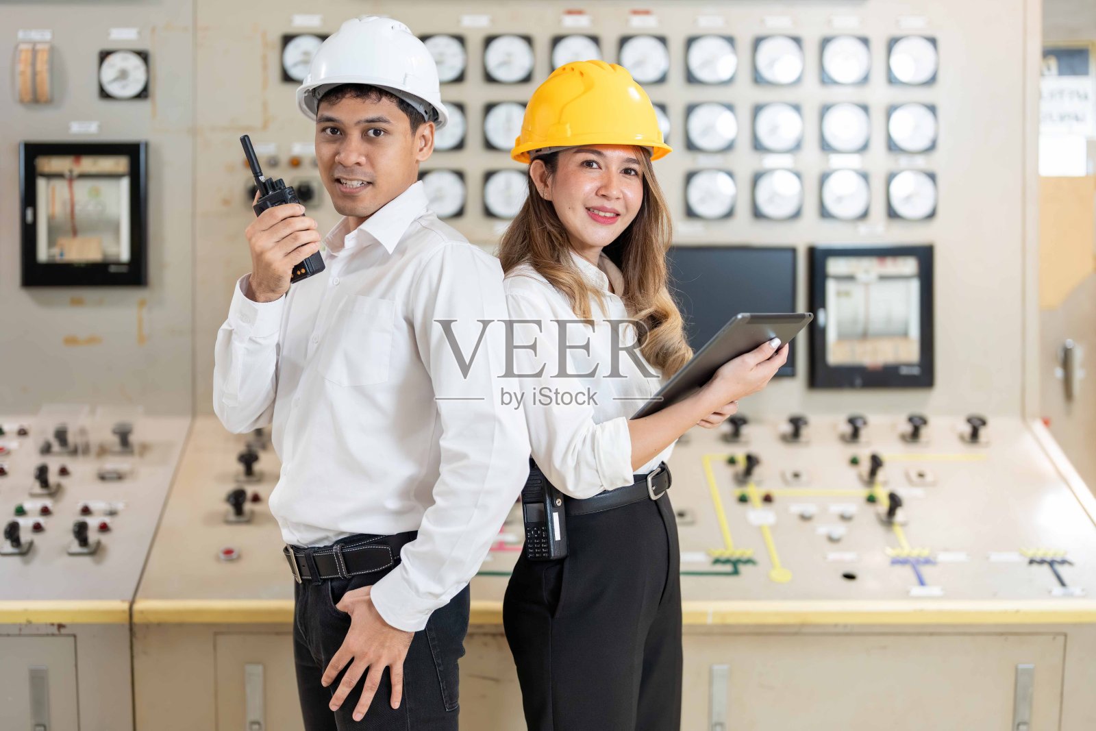 在工业领域的创新方面,两名亚洲工程师在发电厂协调活动,依靠笔记本电脑指导他们推进发电技术的努力。照片摄影图片