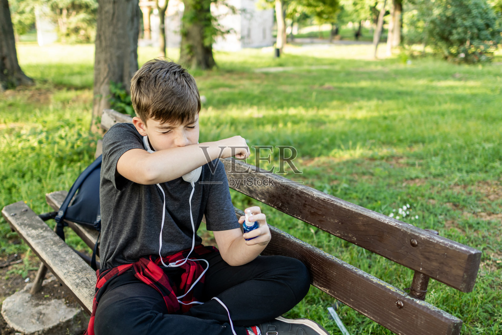 春季哮喘过敏:男孩在公园使用哮喘吸入器和鼻腔喷雾剂照片摄影图片