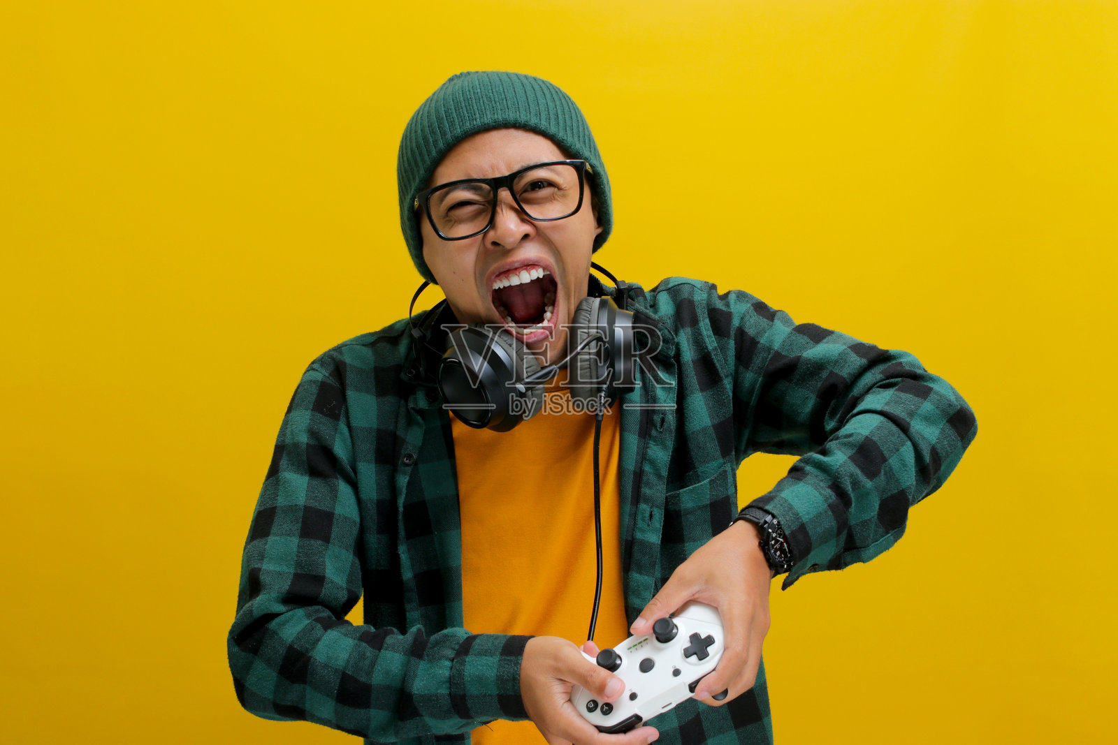 一名愤怒的亚洲年轻人在使用游戏机手柄玩电子游戏时显得很紧张照片摄影图片