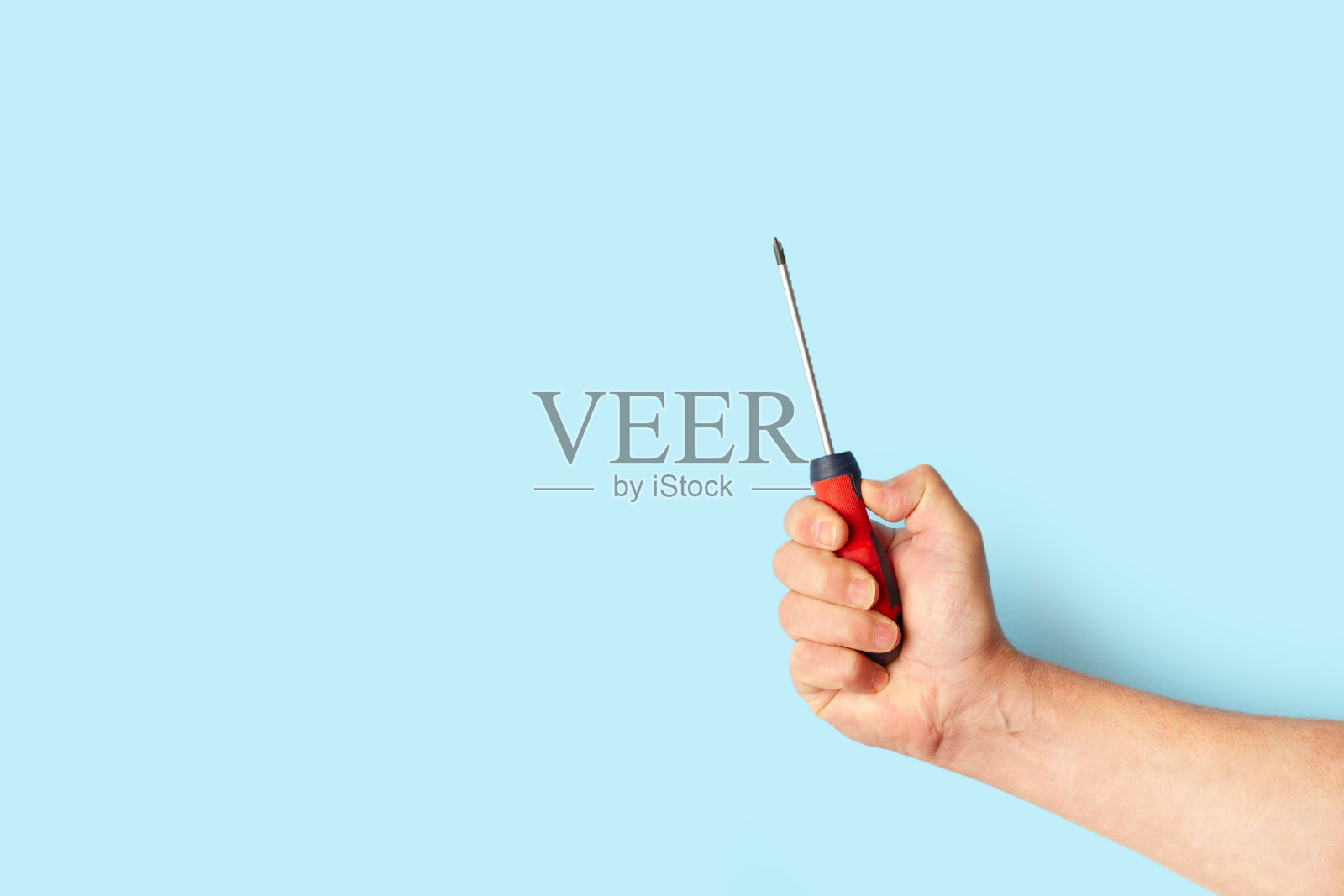 男子手握螺丝刀在浅蓝色背景与复制空间照片摄影图片