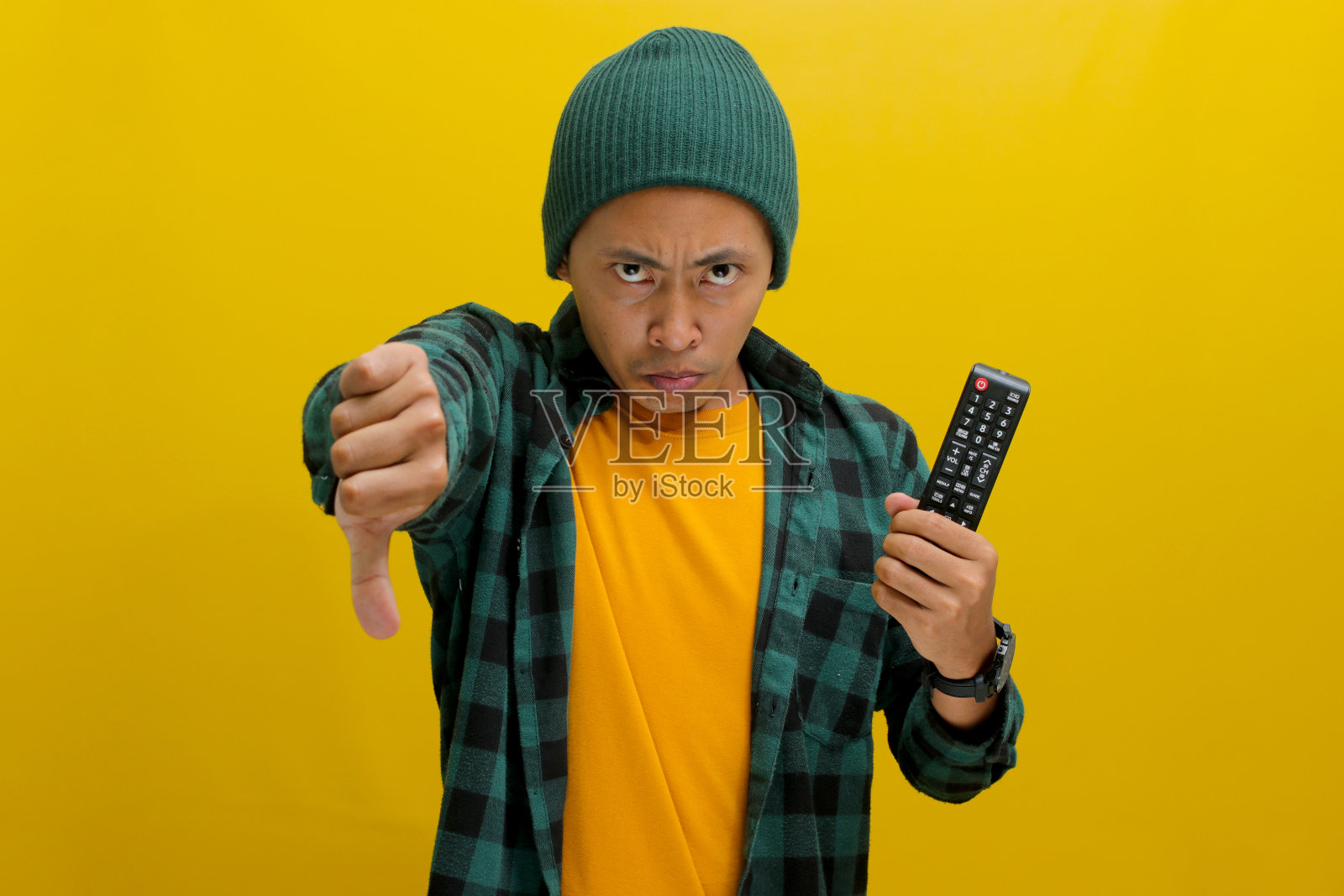 不高兴的亚洲年轻人对一个糟糕的电视节目竖起大拇指照片摄影图片