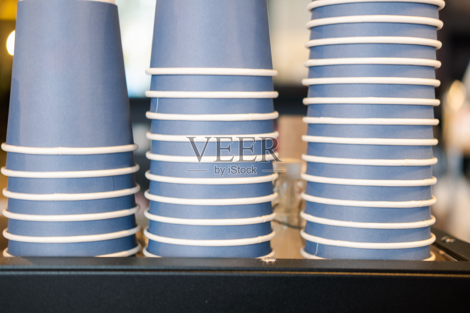 咖啡馆的咖啡机上整齐地摆放着一堆蓝色的纸杯。照片摄影图片