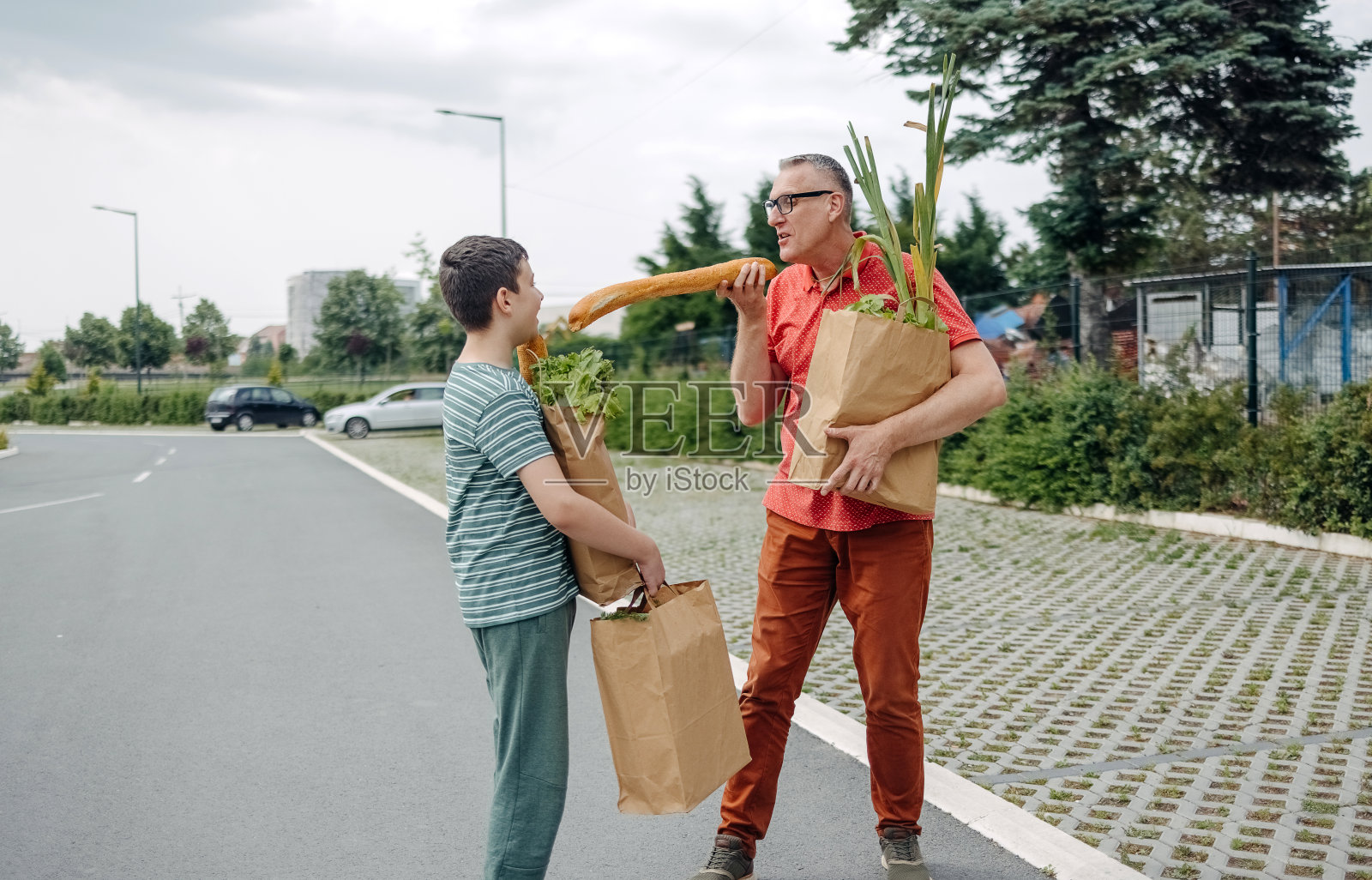 父子俩买完东西拎着纸袋走向汽车,玩得很开心照片摄影图片